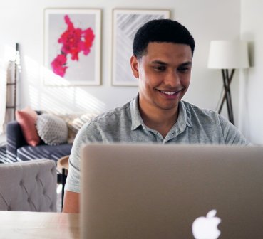 man looking at a computer with two women talking in the background